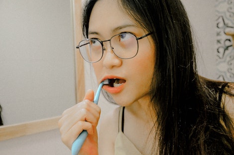 Chica con gafas que se limpia los dientes
